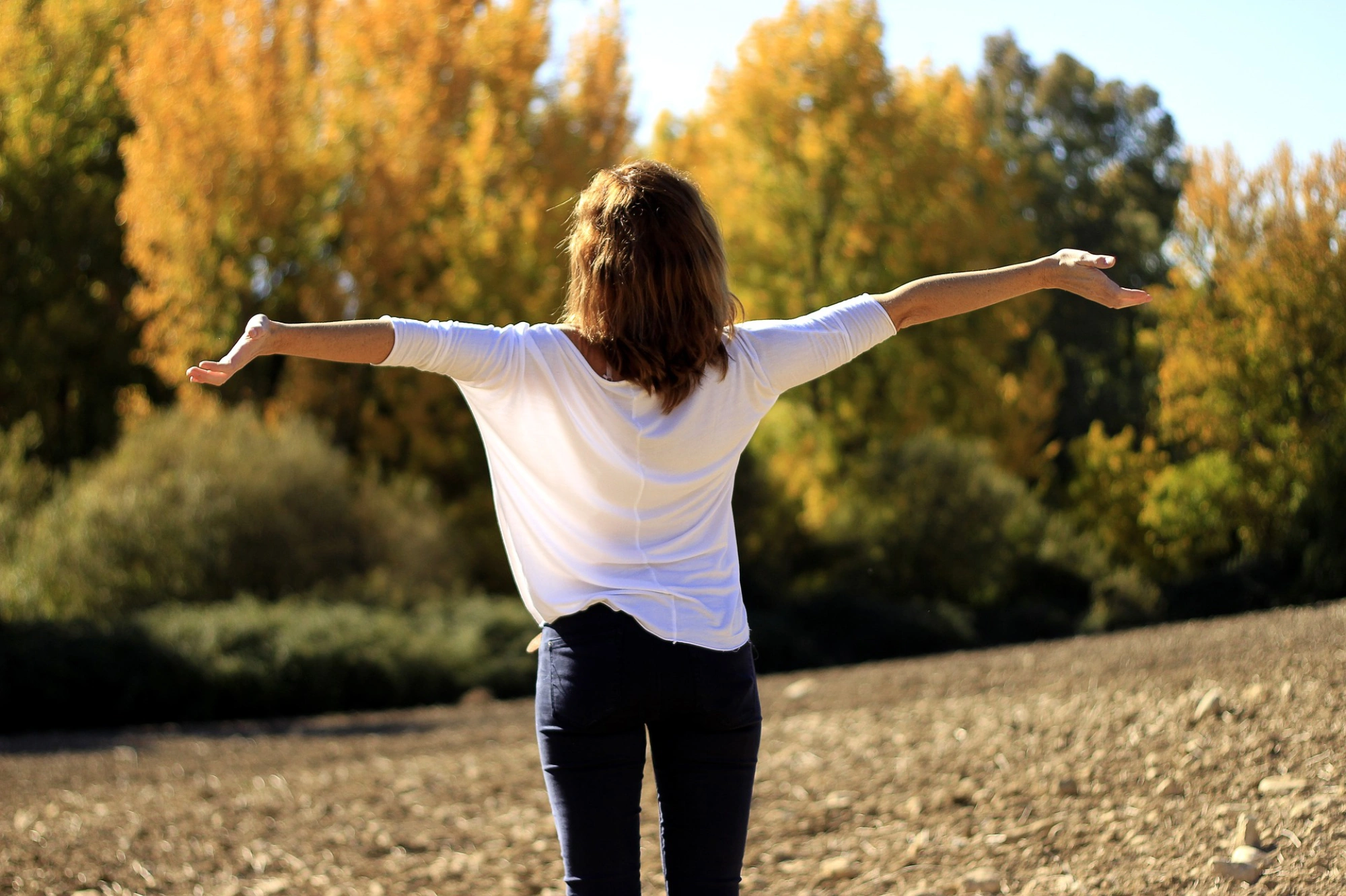 bras écartés, paumes levées, femme pleine de confiance face à la campagne,