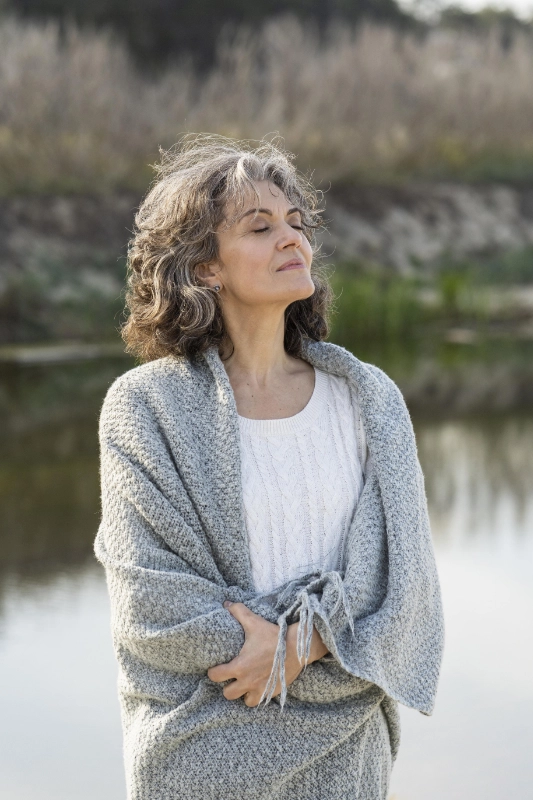 femme sereine respirant l'air frais au bord d'un lac