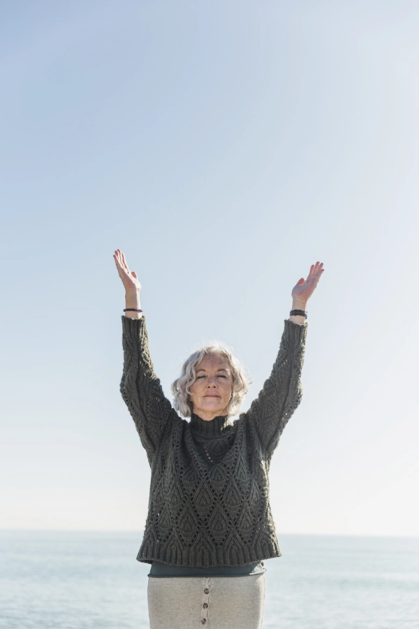 femme âgée, bras en l'air, en bord de mer, savourant le bien être et la sérénité